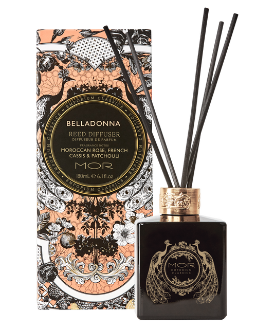 A black glass reed diffuser with gold and white floral patterns and a gold diffuser cap, alongside its decorative box with similar designs.