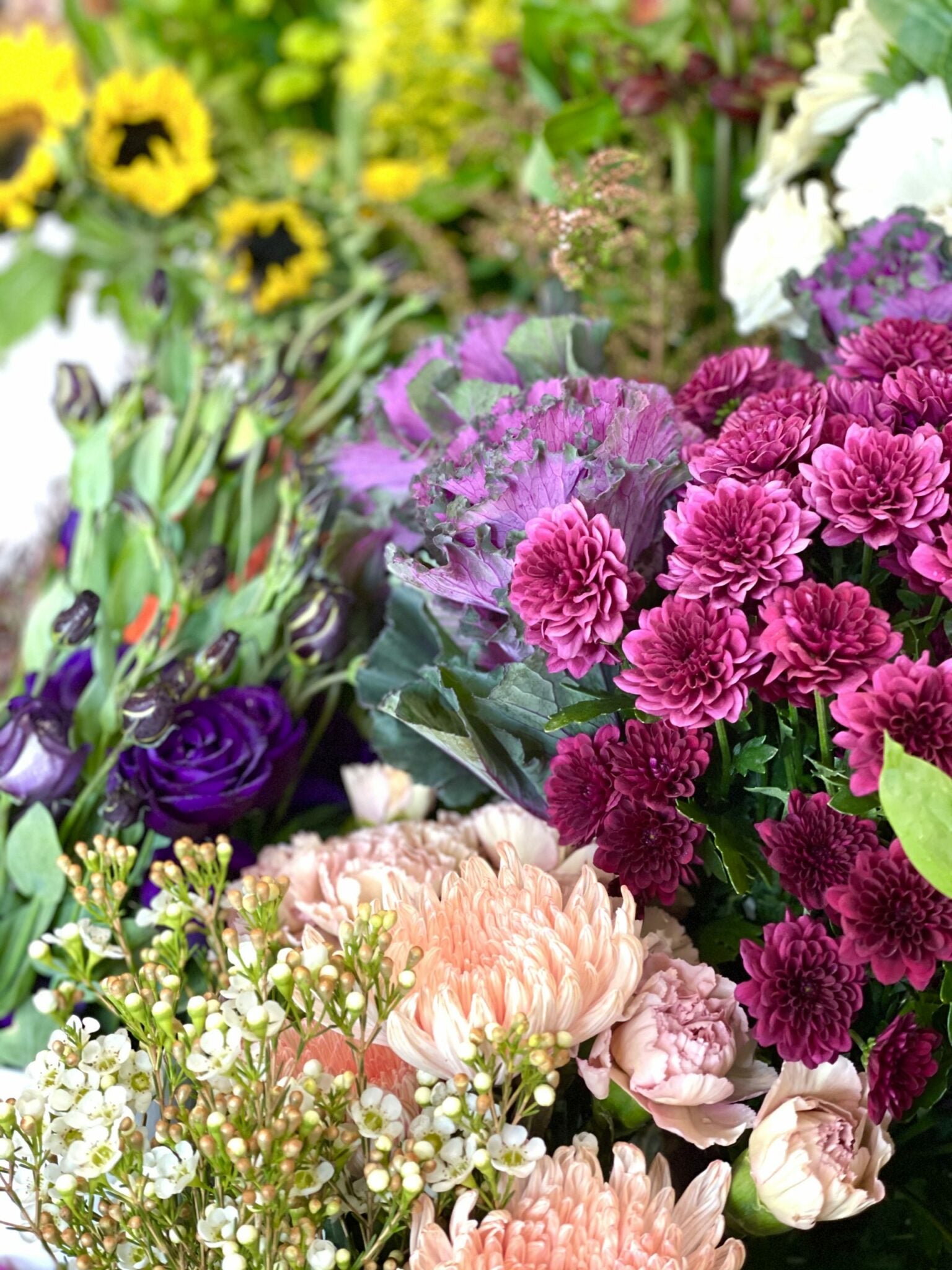 A vibrant bouquet of various flowers including sunflowers, purple flowers, and other seasonal blooms arranged together.
