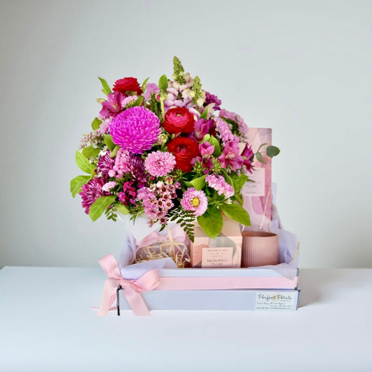 A gift hamper set including a bright pink flower arrangement, a Bramble Bay Co Murunga Plum scented candle, and a fragrance diffuser, all presented in a box with a pink ribbon.