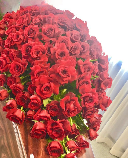 A casket spray of red roses, indicating a funeral tribute.