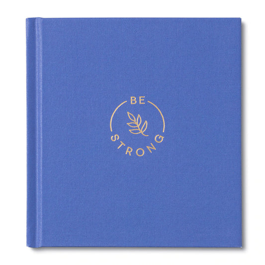 A blue hardcover book with the title 'BE STRONG' embossed in gold foil on the cover, along with a decorative leaf motif.