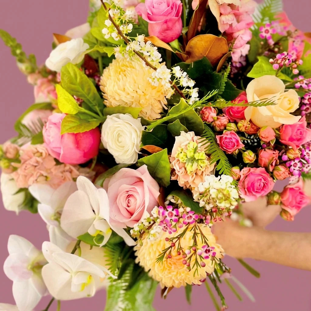 Pastel bouquet of roses, orchids and chrysanthemums on a pink background