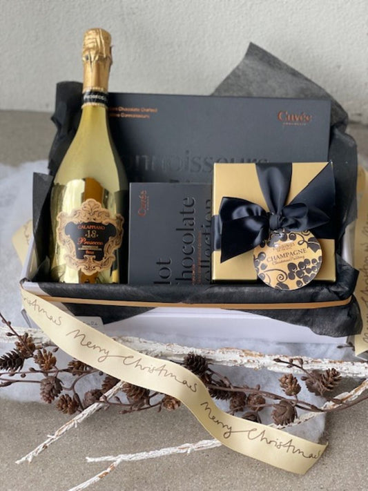 Christmas hamper featuring quality prosecco, gourmet chocolates and Christmas pudding. Luxe black and gold theme.