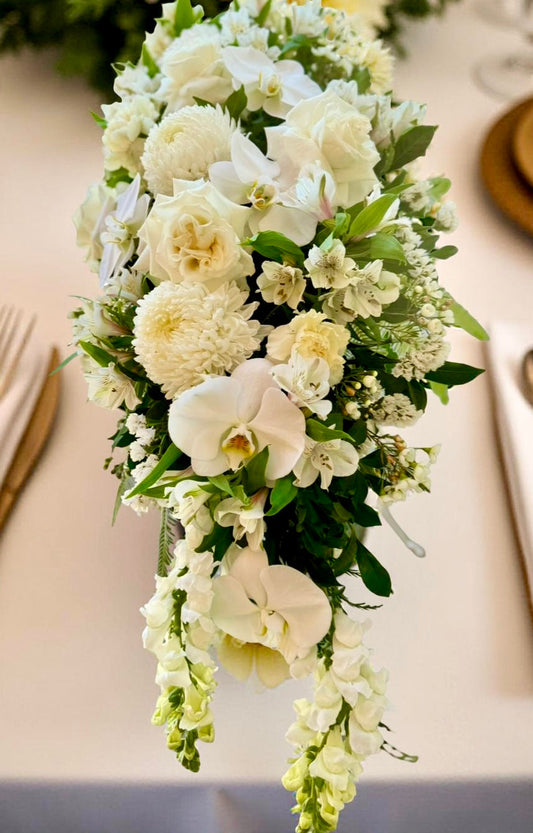 luxury white centrepiece containing roses, orchids and lush white flowers