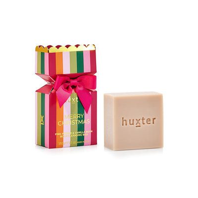 Huxter body cleansing bar beside its mulberry striped Christmas bon bon wrap with a bow