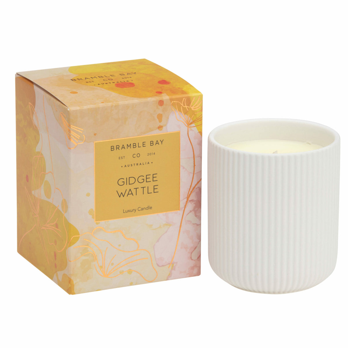 A Bramble Bay Co Gidgee Wattle white ceramic candle with a coppery rose foil lid, labeled 'Gidgee Wattle' by Bramble Bay Co. with 'Australian Native' fragrance, displayed next to its box with abstract Australian floral artwork.