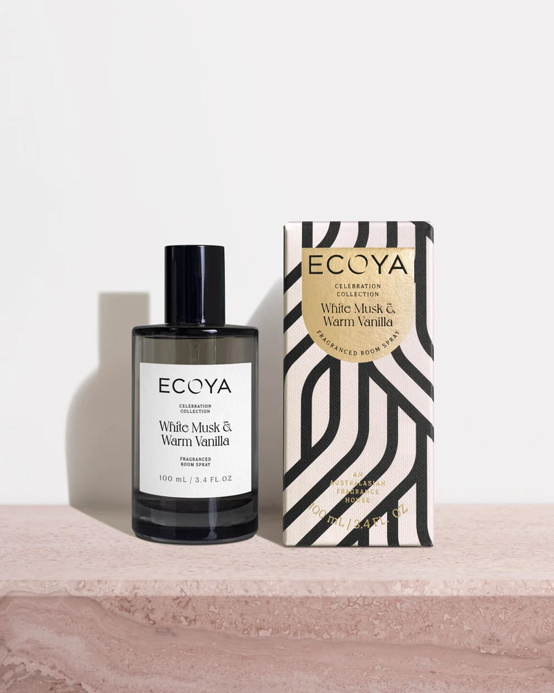 A bottle of Ecoya Celebration Room Spray next to its packaging box, with a black cap, clear bottle, and label, placed on a marble surface.
