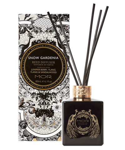 A MOR black glass reed diffuser bottle with gold details, containing a snow gardenia fragrance, displayed alongside its decorative packaging.