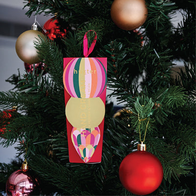 Huxter mulberry striped hand cream gift box hanging on a Christmas tree with red baubles