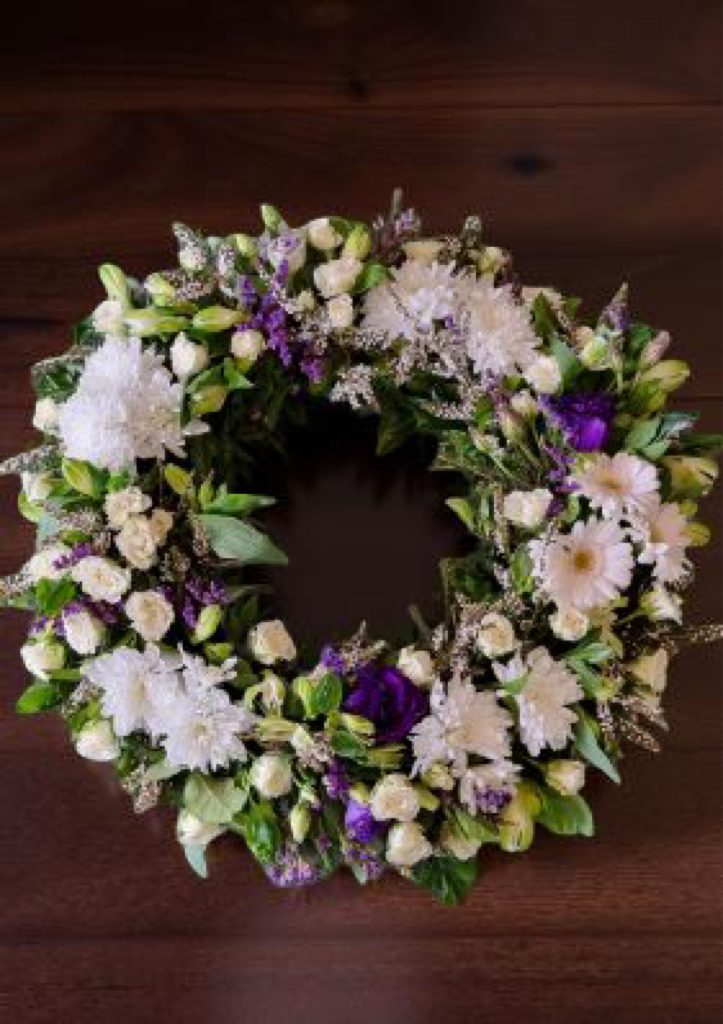 sympathy wreath of white and mauve flowers
