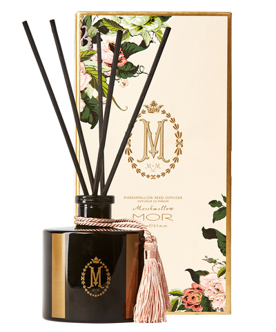 A black reed diffuser with a tassel on top, inside a square-shaped glass jar with a black lid. The product is adorned with a floral pattern and has the 'Mor' brand logo.