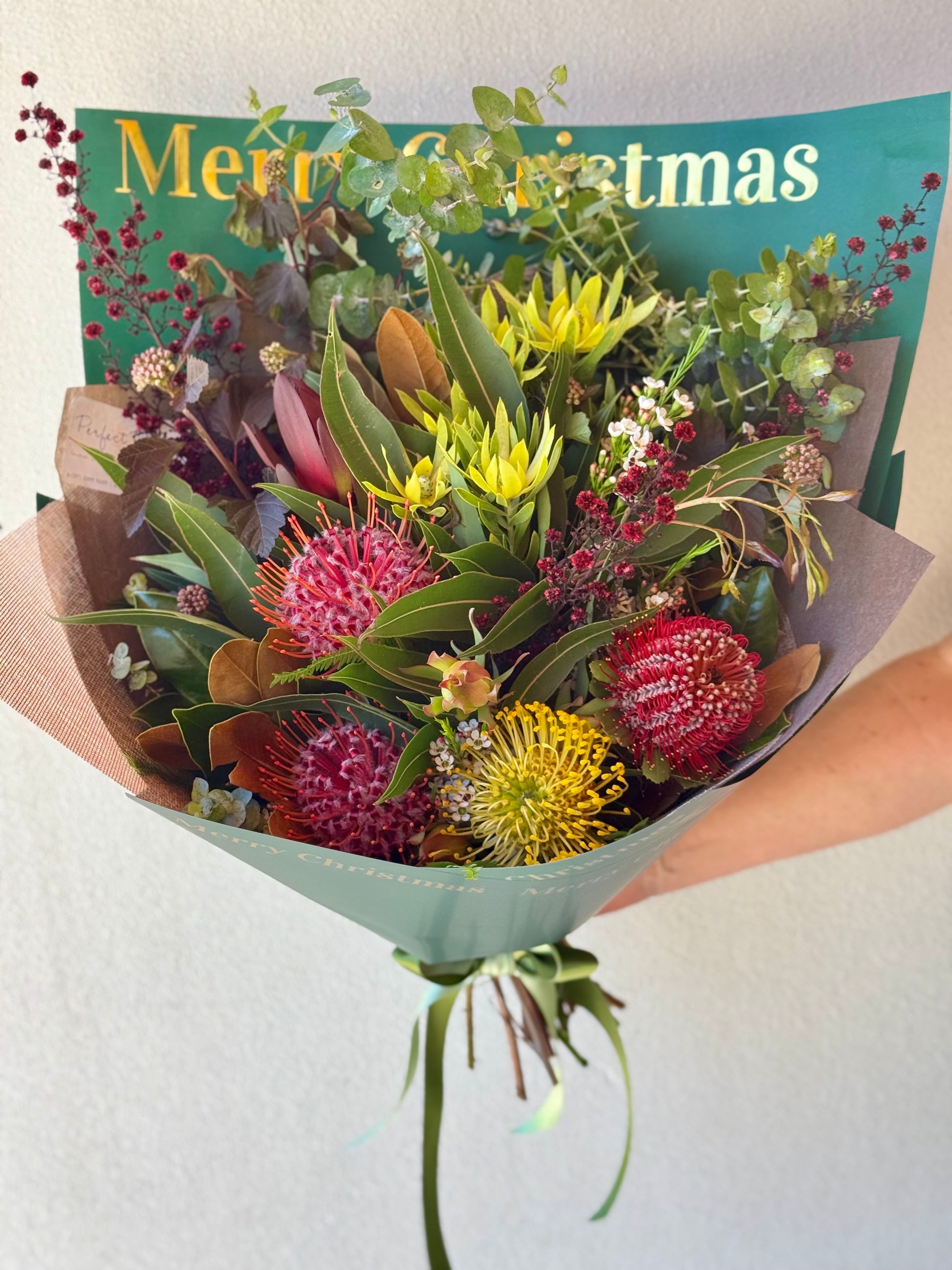 Bouquet of native flowers wrapped in Merry Christmas paper