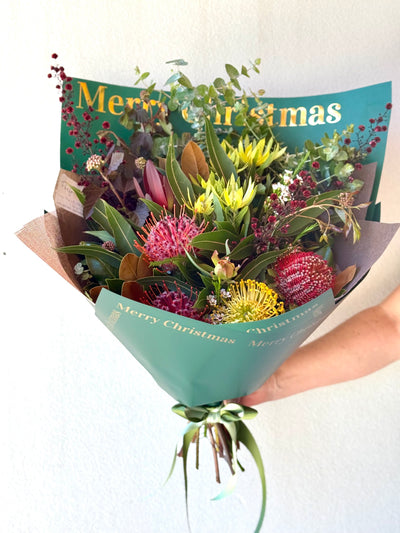 Bouquet of flowers wrapped in green paper with 'Merry Christmas' text on a white background