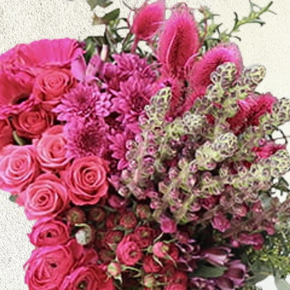 An arrangement of pink flowers, featuring varieties such as roses and other floral blooms, tied with a ribbon.