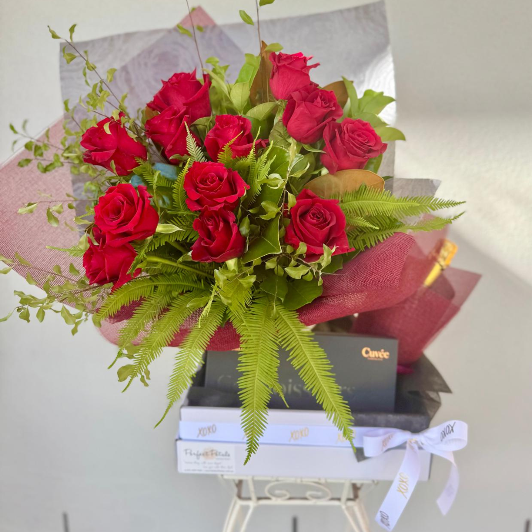 A gift set including a bouquet of red roses and a box of chocolates and a bottle of gold prosecco.
