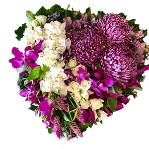 A heart-shaped floral arrangement with a mix of pink and white flowers, including roses and orchids.